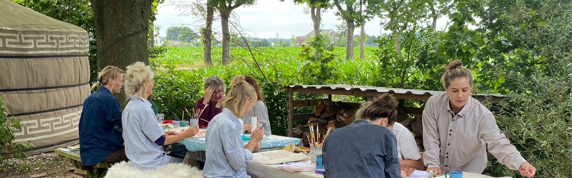 Groep deelnemers schildert samen tijdens een creatieve workshop op maat van Slow Creative